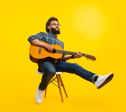 Handsome hipster musician man sitting and playing guitar. 