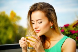 Young Woman Drinking Green Tea Outdoors. Summer Background. Shallow Depth of Field.