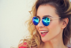 Close Up Portrait of Happy Fashion Woman in Sunglasses. Smiling Trendy Girl in Summer. Laughing Female. White Wall Background Copy Space. Not Isolated Toned Photo.
