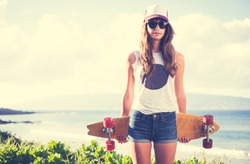 Beautiful hipster girl with skate board wearing sunglasses