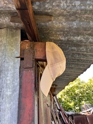 Side view on a headgear hanging under aluminium roof in the garden. A cap, or hat, is a kind of head dress that protects you from straight sunrays