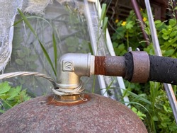 Closeup of a new metal faucet (valve) installed on a rusty vessel to connect flexible pipe. Connection of valve and old pipe with rusty thread. Rusty iron against blurry background