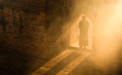 Silhouette of muslim man having worship and praying for fasting and Eid of Islam culture in old mosque with lighting and smoke background              