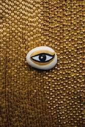 hand painted white, gold, black evil eye rock in the middle of gold sequin fabric. ancient egyptian theme