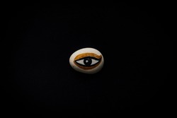 hand painted white, gold, black evil eye rock in the middle of black. Ancient Egypt theme.