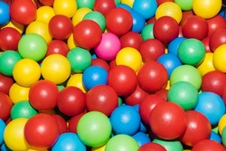 Many colour plastic balls from children's small town. Background texture of multi-colored plastic balls. Colorful plastic gum balls in kid playroom or playground for children's holiday party concept