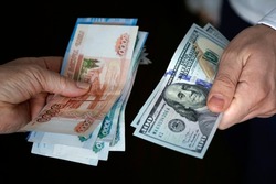 Hands holding russian rouble and us dollar bills. dollars and rubles. concept of currency exchange.
