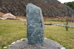 A stone with a deer pattern on the background of nature. Prehistoric attraction Altai.