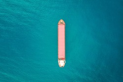 Red color container ship at sea shot from above. Scenic waterscape and lonely boat engaged in export and import business and logistics. Shipping cargo. Water transport. Aerial view of the sea and boat