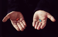 Red tablet in the left palm blue pill in his right hand