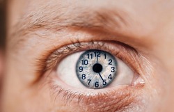 Concept of aging, time flies of man. Clock dial on eye. Close-up