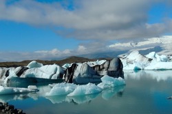 Bright clear blue and black stripped icebergs floating in the Jokulsarlon lake blue cold water in Iceland iceberg floating in the Jokulsarlon lake blue cold water in Iceland