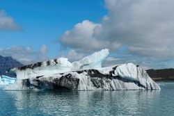 Bright clear blue and black iceberg floating in the Jokulsarlon lake blue cold water in Iceland