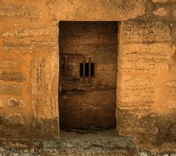 door of an ancient abandoned prison built in wood with an iron bolt and a small window with iron bars