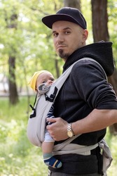 close up of father carrying his child in a baby sling