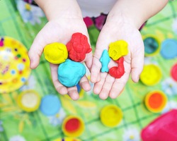 Child hands playing with colorful clay, plasticine in children's room, Creative playing with baby play dough, hands holding hand-made plasticine toy, making plasticine figures