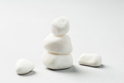 Stacked White zen rocks balance on the grey background. Balancing pebble stones 
