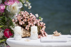 Wedding table with bouquet of flowers cream pink roses and accessories on the caribbean seashore in summer sunny day