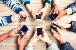 Hands circle using phones on table top view - Multiracial people holding mobile devices sitting around at office desk - Concept of friends team working and modern communication technology above image 