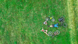 Family cycling on bikes outdoors aerial view from above, happy active parents with child have fun and relax on grass, family sport and fitness
