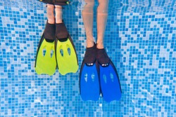 Underwater kids legs in fins in swimming pool