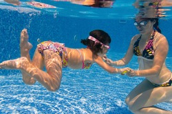 Underwater family in swimming pool. Mother teaching her child
