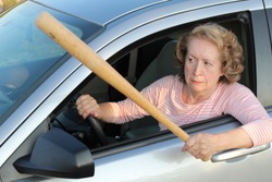 Angry mature female driver holding baseball bat 