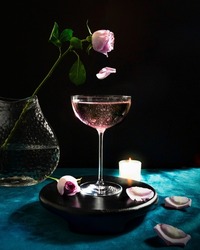 Champagne cocktails with pink rose and a candle for a romantic atmosphere