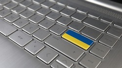 Keyboard with Ukraine flag on the enter button, represents cyber attack of Ukraine, metaphor of learning Ukrainian language, grey keypad close up, front view, selective focus