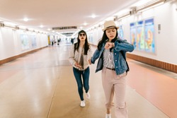 asian sisters are in a rush to catch the train. female travelers running in the passageway in the railway station. backpacker self-guided trip in USA concept.