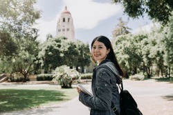 female college student join short term summer tour program to learn language well in university. young girl study abroad in stanford. asian woman face camera smiling holding school book go to class