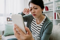 korean female getting tired eyes from using smartphone for long hours without resting. portrait of asian woman with asthenopia is rubbing her eye and struggling to focus her vision.