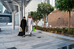 Saudi Arab couple shopping outdoor carrying mall bags. Muslim family walking happy in summer enjoying the gifts wearing abaya and traditional dress