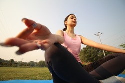 Extreme wide angle shot of an indian girl doing yoga in the park early in the morning.Healthy lifestyle concept.