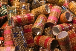 Background of colorful bangles stacked in a shop in India with glitter and plain colored bangles. The bangles are made of glass, metal or lac and worn regularly or on special occasions by Indian women