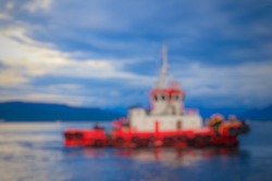 defocus and blurred image of a red harbor tug or tug boat sailing on a blue sea with a beautiful sky background. copy space and negative space for writing remarks. Beautiful ship voyage at the morning