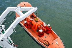 process of launching a rescue boat into the sea, releasing a life boat to perform abandon ship safety drills and man recovery for man overboard drills on board. Davit crane is lowering the life boat