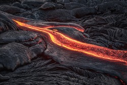 Red lava flow from black volcanic ground on melted dark background