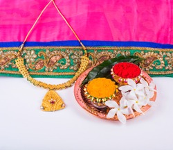 
Mangalsutra or Golden Necklace to wear by a married hindu women, arranged with traditional saree with haldi, kumkum and flowers on plate.