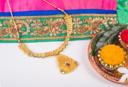 Mangalsutra or Golden Necklace to wear by a married hindu women, arranged with traditional saree with haldi, kumkum and flowers on plate.