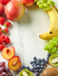 frame of fresh fruit and berries on kitchen table, top view