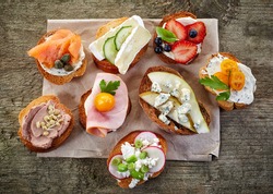 collection of toasted bread slices with various cheese and meats, top view