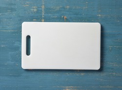 white plastic cutting board on blue wood table, top view