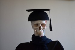 Skeleton Oscar or Skeleton Arthur arthur in american student outfit for graduation and his mortarboard.