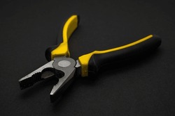 Used combination pliers, close up on black surface