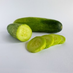 Cheap fresh cucumber with some cucumber slices isolated on white background.  cheap groceries.