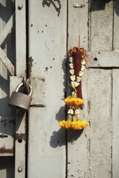 Incongruous glimpse of faith: old metal door, lock, and flower garland and burned incense stick