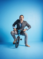 Nerdy businessman riding a small bicycle