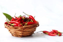 Red Bird's Eye Chilli, Red Chilli Padi, Bird Chilli, a heap of Thai pepper placed in a wooden basket over white marble background. copy space. 