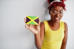 African american woman with afro hair, wear yellow singlet and eyeglasses, hold Jamaica flag isolated on white background.